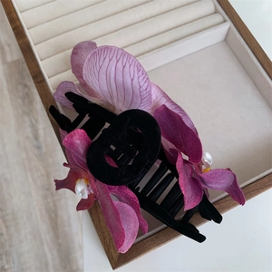 Macro shot of orchid petal hair clip with black velvet base and pearl CD logo detail