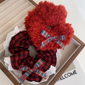 Detail of red plush hair scrunchie and plaid lace scrunchie with festive bows
