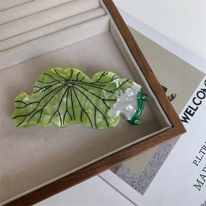 Détail d'une pince à cheveux feuille de lotus marbrée verte avec décor de grenouille
