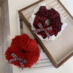 Detailed close-up of red plaid scrunchies with white lace and plush velvet material