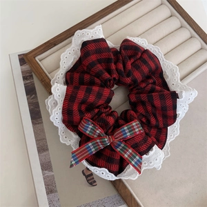 Detail view of red plaid scrunchie with white lace edges and sweet bow decoration