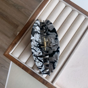 Détail d'une grande pince à cheveux en acétate avec texture marbre noir et blanc et ressort doré