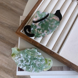 Unique teapot-shaped acetate hair claws with marble textures in green and pink colors
