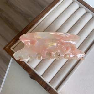 Détail de la pince à cheveux en acétate marbré pêche et crème sur support velours