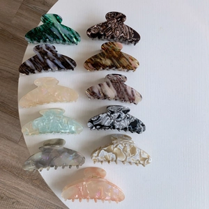 Set of 11 large acetate hair claws with marble and tortoiseshell textures on white stand