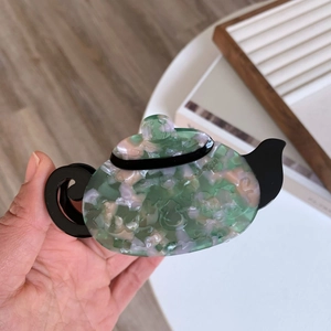 Close-up of teapot hair claw clip with green and pink acetate marble texture pattern