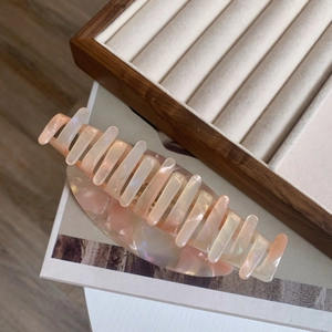 Détail d'une grande pince à cheveux élégante en acétate rose nacré avec texture marbrée chic