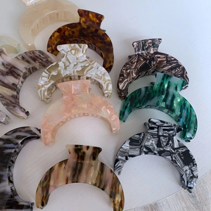 Detailed view of large crescent acetate hair claws in various marble and tortoiseshell patterns