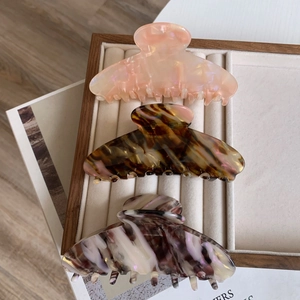 Detailed view of three acetate hair claws in marble and tortoiseshell patterns on a tray