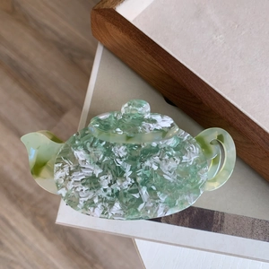 Detailed texture of acetate shark hair claw clip in teapot shape with marbled green patterns
