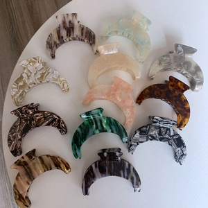Macro detail of large crescent acetate hair claws featuring marble and tortoiseshell patterns