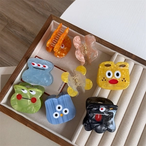 Detailed close-up of cartoon acetate hair claws with marble texture and funny expressions