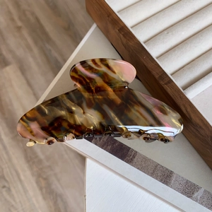 Detail of large acetate hair claw with amber tortoise shell pattern and glossy finish