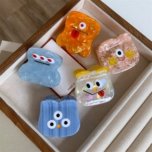 Five colorful cartoon monster acetate hair claws with funny expressions on a velvet tray