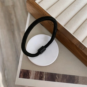 Detail of high-elasticity black hair tie featuring a sleek cylindrical plastic connector