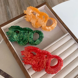 Haarklemmen van acetaat in de vorm van een draak in rood, groen en geel met gouden patroon