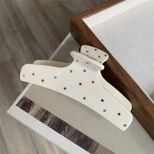Close-up of cream white acetate hair claw clip with colorful rhinestones detail
