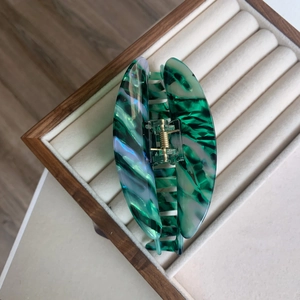 Détail d'une pince à cheveux en acétate marbré vert émeraude avec ressort en métal doré
