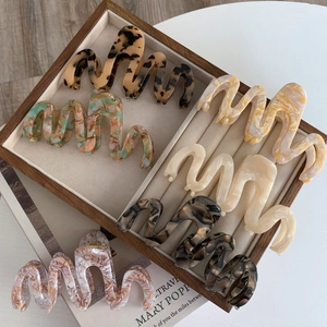 Close-up of oversized wavy acetate hair claws in various marble and tortoiseshell patterns