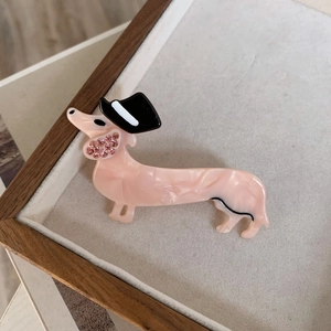 Dettaglio del fermaglio a forma di bassotto in acetato rosa con strass e cappello retrò