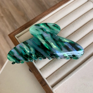 Detailed macro view of large acetate hair claw clip with green marble texture and pearlescent finish