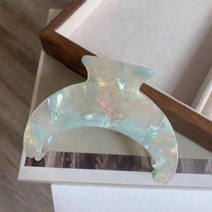 Macro shot of large crescent acetate hair claw clip with iridescent pearl texture