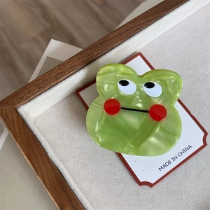 Detail of cute green marble textured acetate monster claw clip on wooden display