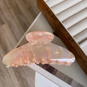 Detailed view of large pink marble acetate hair claw clip with pearlescent finish