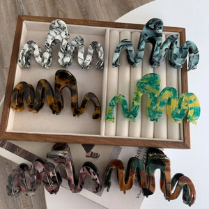 Close-up of six oversized wavy acetate hair claws in various marble and tortoiseshell patterns