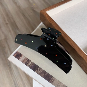 Detail view of black acetate hair claw clip decorated with colorful sparkling rhinestones