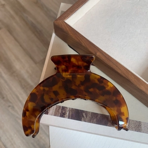 Close-up of a large crescent acetate hair claw clip with brown tortoiseshell pattern