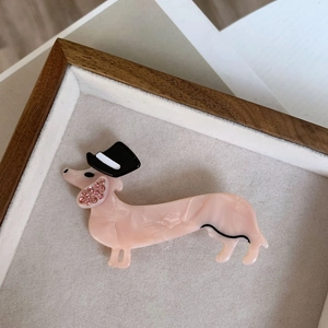 Dettaglio del fermaglio per capelli bassotto in marmo rosa con cappello nero e strass