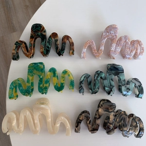 Detail view of large wavy acetate hair claws in various marble and tortoiseshell patterns