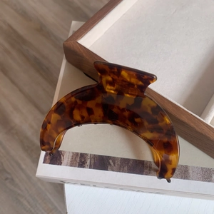 Macro shot of large acetate crescent hair claw with tortoise pattern on wooden tray