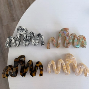 Detailed view of four acetate hair claws in zebra, colorful, leopard, and marble patterns