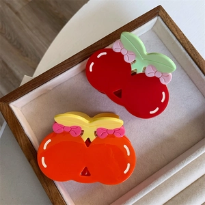 Detail of colorful acetate cherry hair claws with bows on a velvet jewelry tray