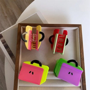 Detail view of colorful acetate handbag-shaped hair claws on a wooden jewelry tray