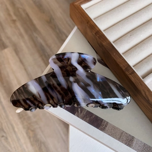 Detail of large acetate hair claw with artistic black and white marble texture