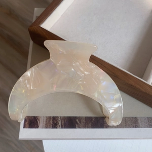 Close-up of large ivory acetate crescent hair claw clip with iridescent marble texture