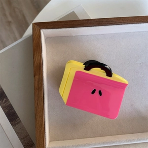 Detail view of pink and yellow bag-shaped acetate hair claw clip on a velvet tray