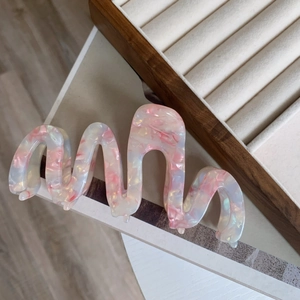 Oversized wavy acetic acid hair claw clip with pink pearlescent marble texture and glossy finish