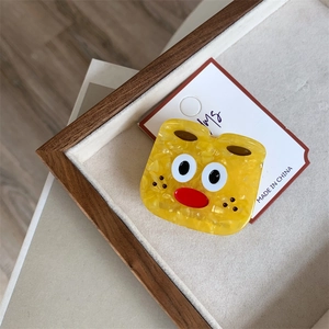 Close-up of yellow cartoon acetate hair claw clip with playful face on wooden tray