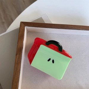 Detail of red and green handbag-shaped hair claw clip with glossy resin finish