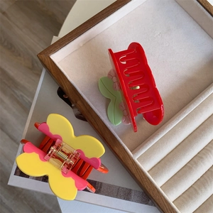 Colorful acetate cherry and butterfly hair claw clips set in a wooden display tray