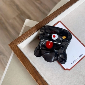 Close-up of funny cartoon shark hair claw clip with red eye and tongue on a wooden tray