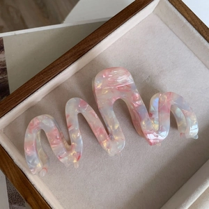 Detail of oversized marble pink acetate hair claw clip with pearlescent wave design
