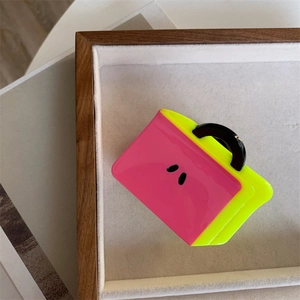 Detail of creative handbag-shaped hair claw clip in bright pink and neon green resin