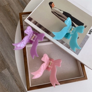 Three-piece acetate bow hair claw set in pink, lavender, and blue with gold springs