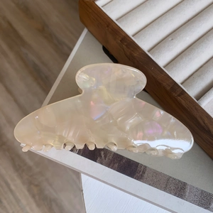 Detailed close-up of ivory acetate hair claw clip with pearlescent texture and rounded teeth