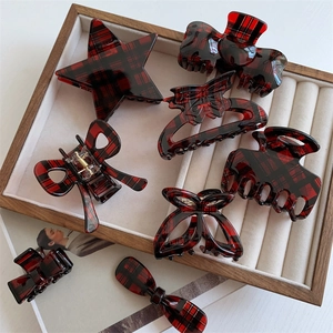 Macro shot of 8-piece set of red and black plaid acetate hair claws and clips in a box
